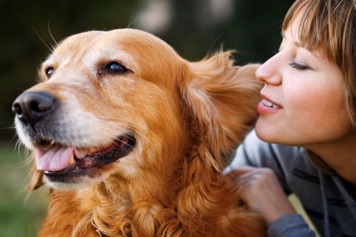 耳元で話しかける女性と犬