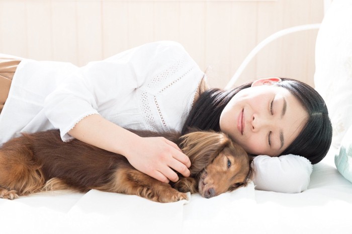 一緒に眠る女性と犬