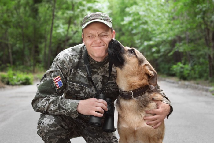 軍のユニフォームを着た男性とジャーマンシェパード