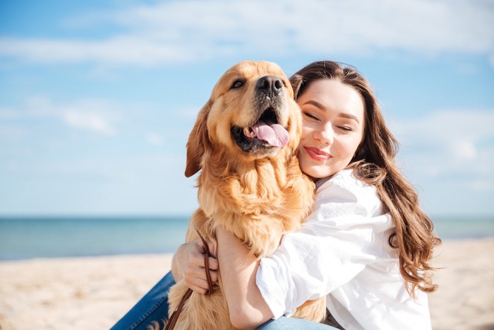 浜辺で犬を抱きしめる女性