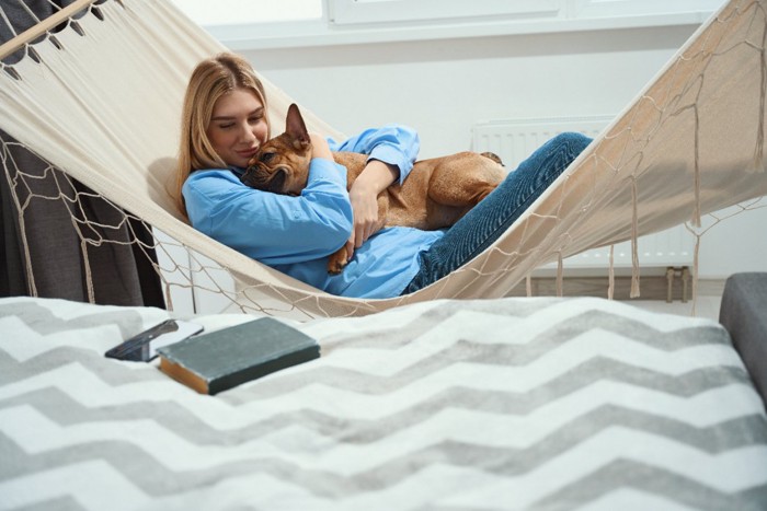 ハンモックで愛犬をハグする女性