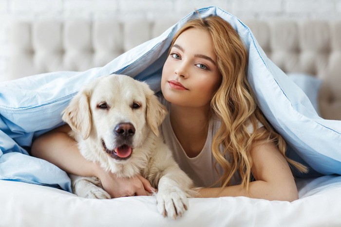 ベッドの中の犬と女性