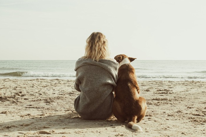 寄り添って座る女性と犬の後ろ姿