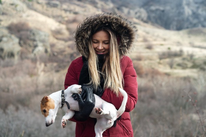 女性に抱っこされて逃げようとする犬