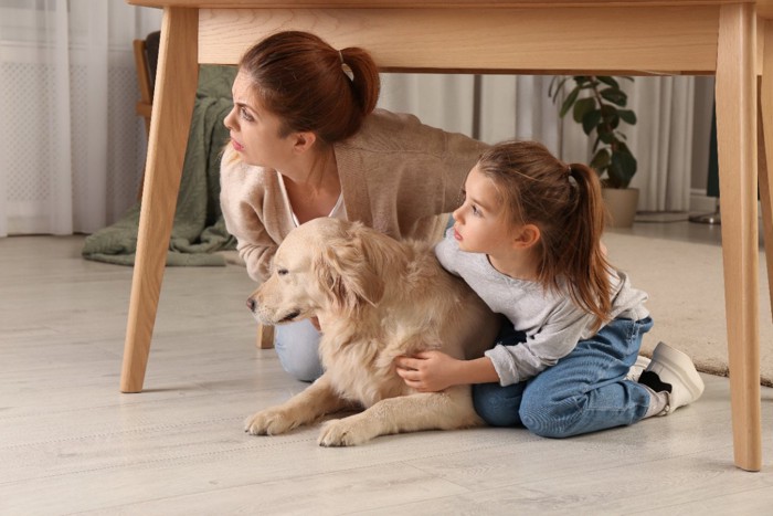 テーブルの下に隠れる家族と犬